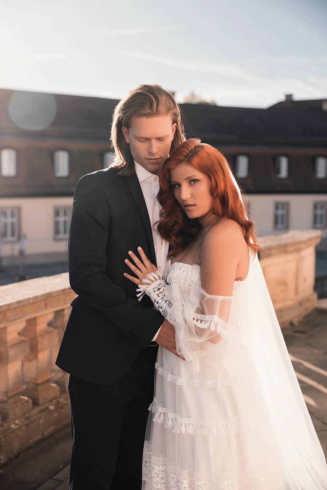 Ein Brautpaar posiert für ein Porträt an einem Schloss. Romantische Hochzeitsfotos mit atemberaubender Aussicht.