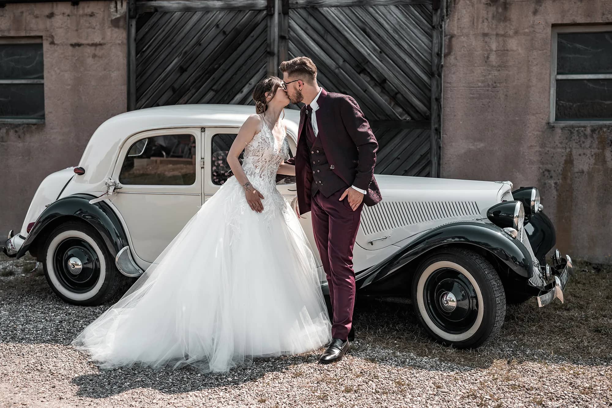 Brautpaar posiert vor einem klassischen Auto bei ihrer Hochzeit in Strasbourg, Frankreich.