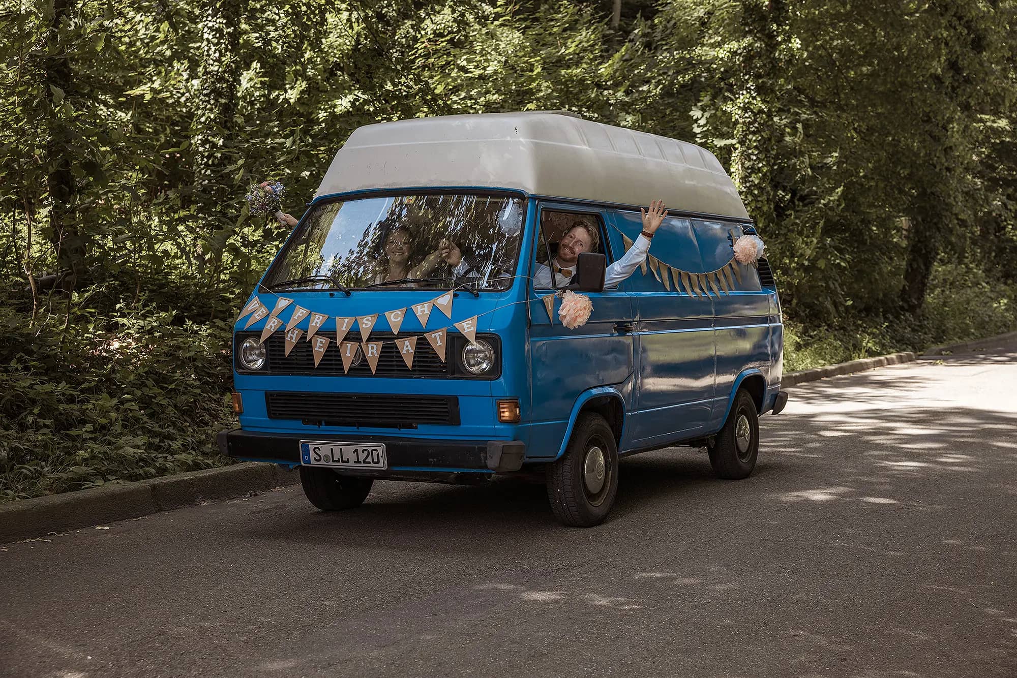 Braut und Bräutigam, fahren in ihrem Hochzeitsauto, dem VW Bus zur Hochzeitslocation am Waldsee in Freiburg